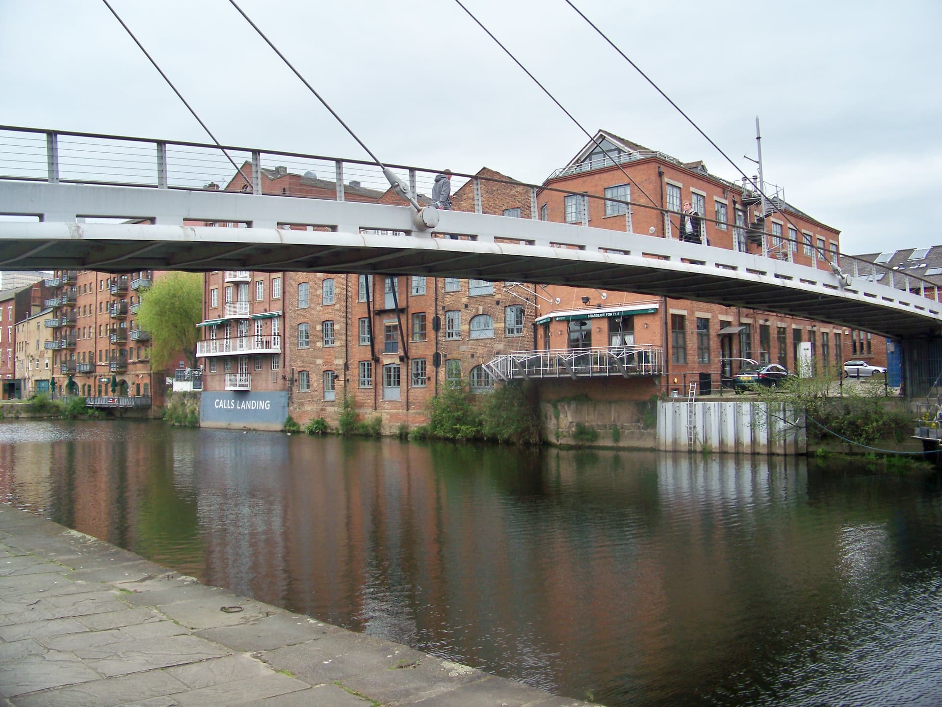 Footbridge over the River Aire with converted red-brick warehouses and flats along The Calls, Leeds